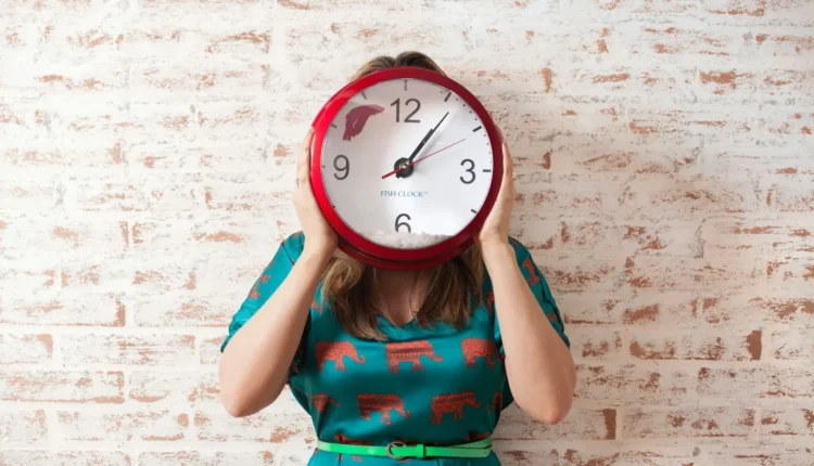 woman covering face using wall clock