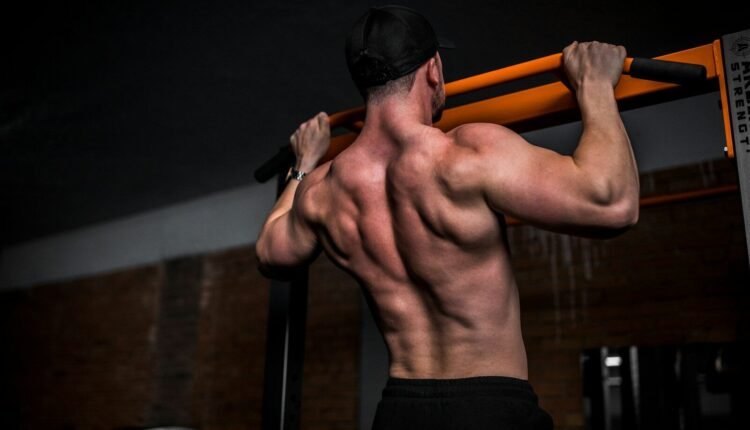 topless man in black shorts holding orange bar