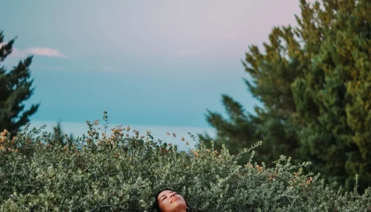 a man lying in a field of plants with water in the background