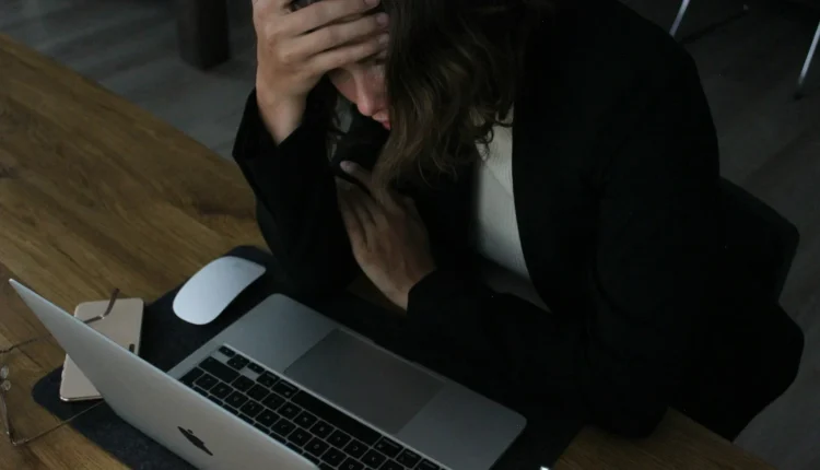 stressed woman with head in hands at laptop