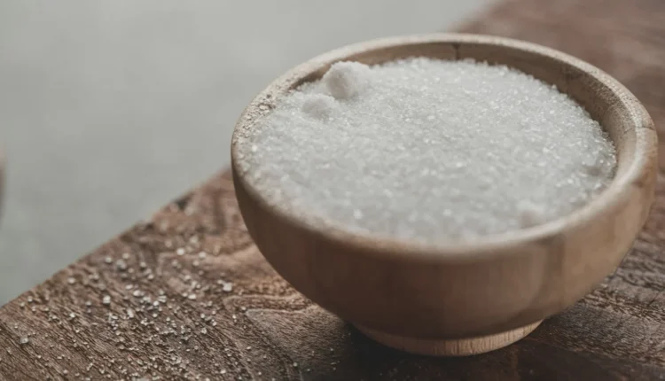 a wooden bowl filled with sugar on top of a wooden table